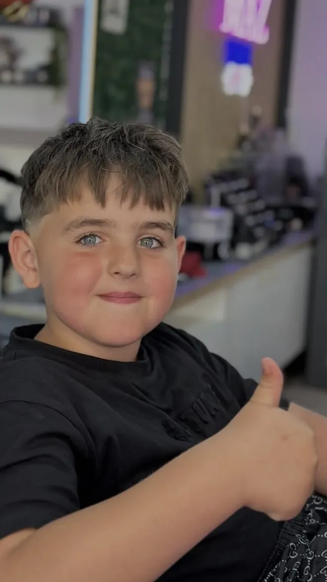 Un enfant content de sa coupe, pouce levé, au salon Maz Barber