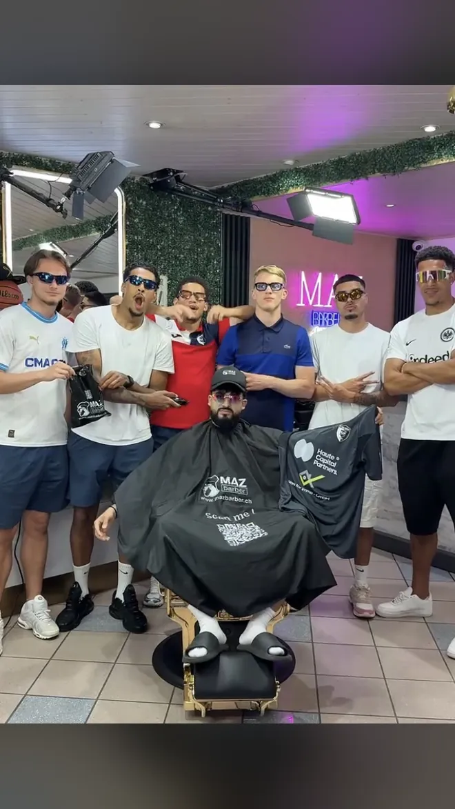 Mazin unter dem Umhang des Salons, umringt von einer Gruppe junger Männer