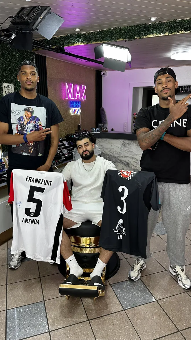 Mazin dans le fauteuil, entre deux joueurs qui tiennent leurs maillots